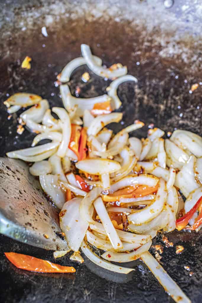 Fried onion and pepper in chili in oil in a wok. 