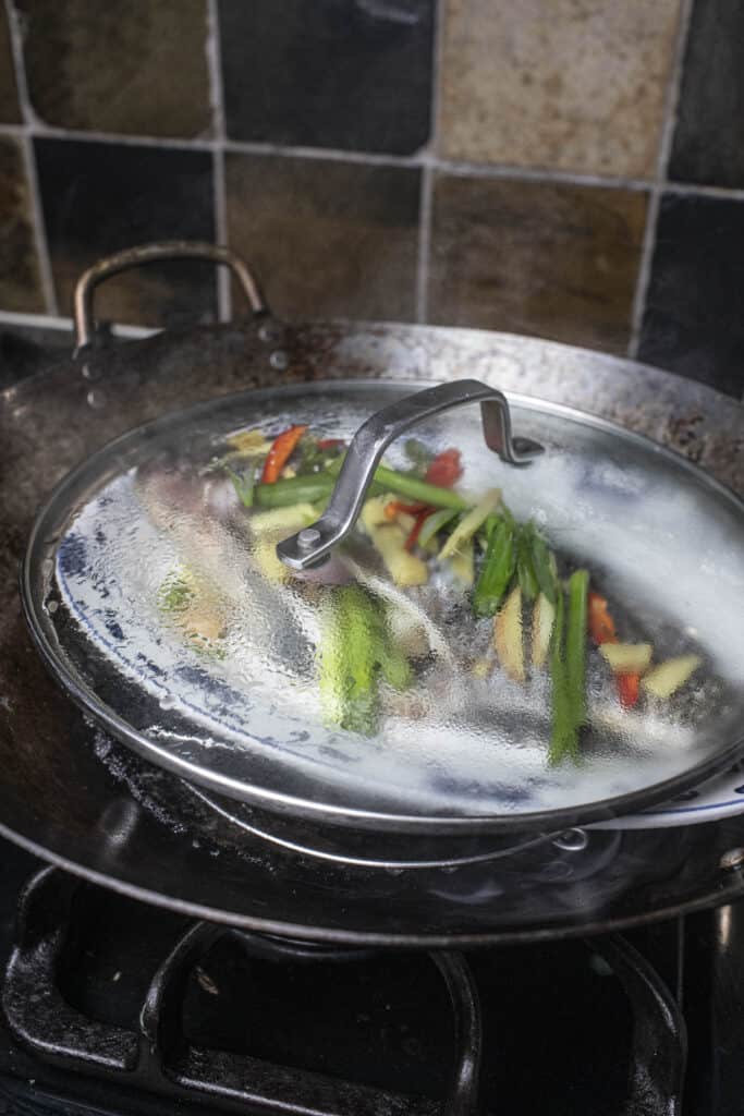 Steamed ginger fish in a wok with  a lid. 