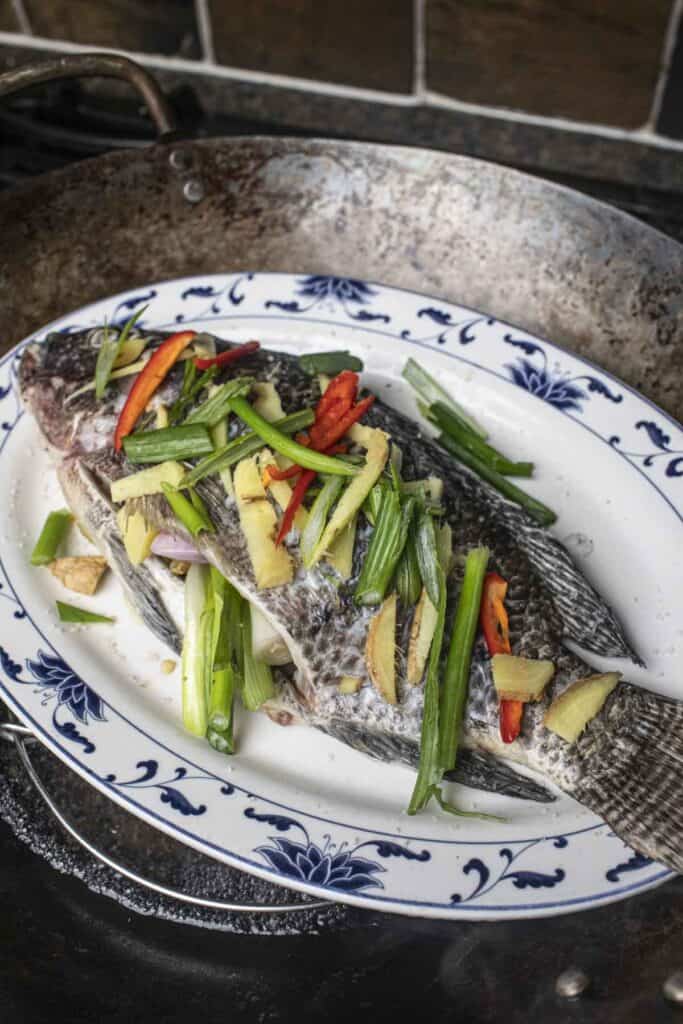 Chinese steamed fish on a platter over a wok. 
