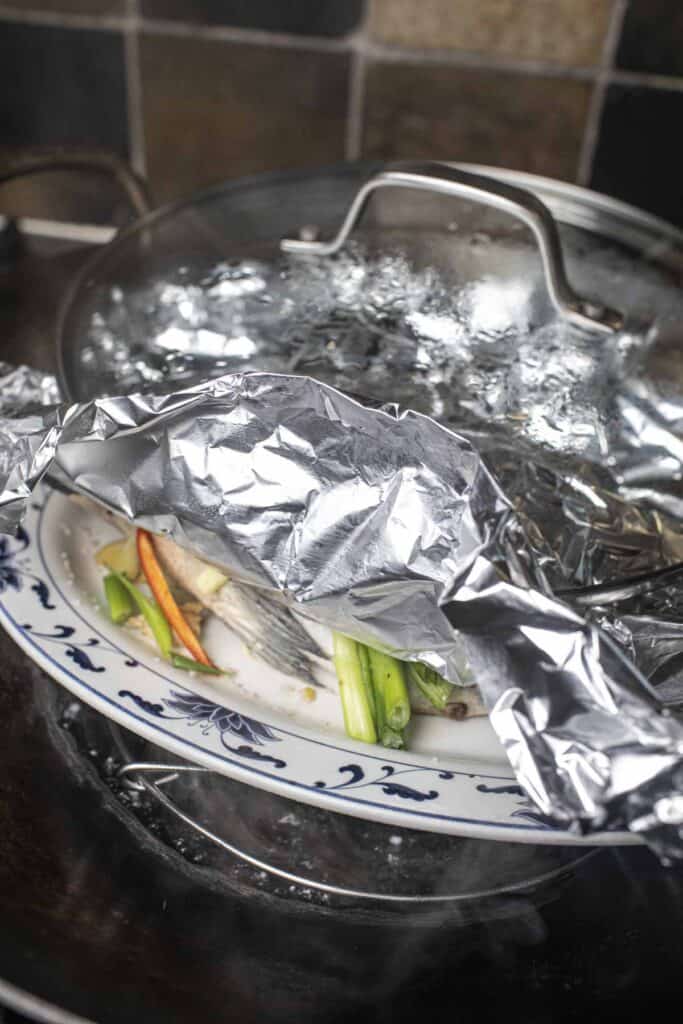 steamed ginger fish in a wok with aluminium and a lid. 