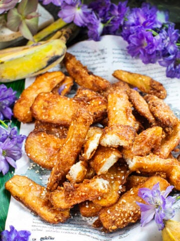 thai fried bananas on a plate with purple flowers.