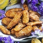 thai fried bananas on a plate with purple flowers.