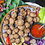 thai pork meatballs luk chin in skewers on a platter.