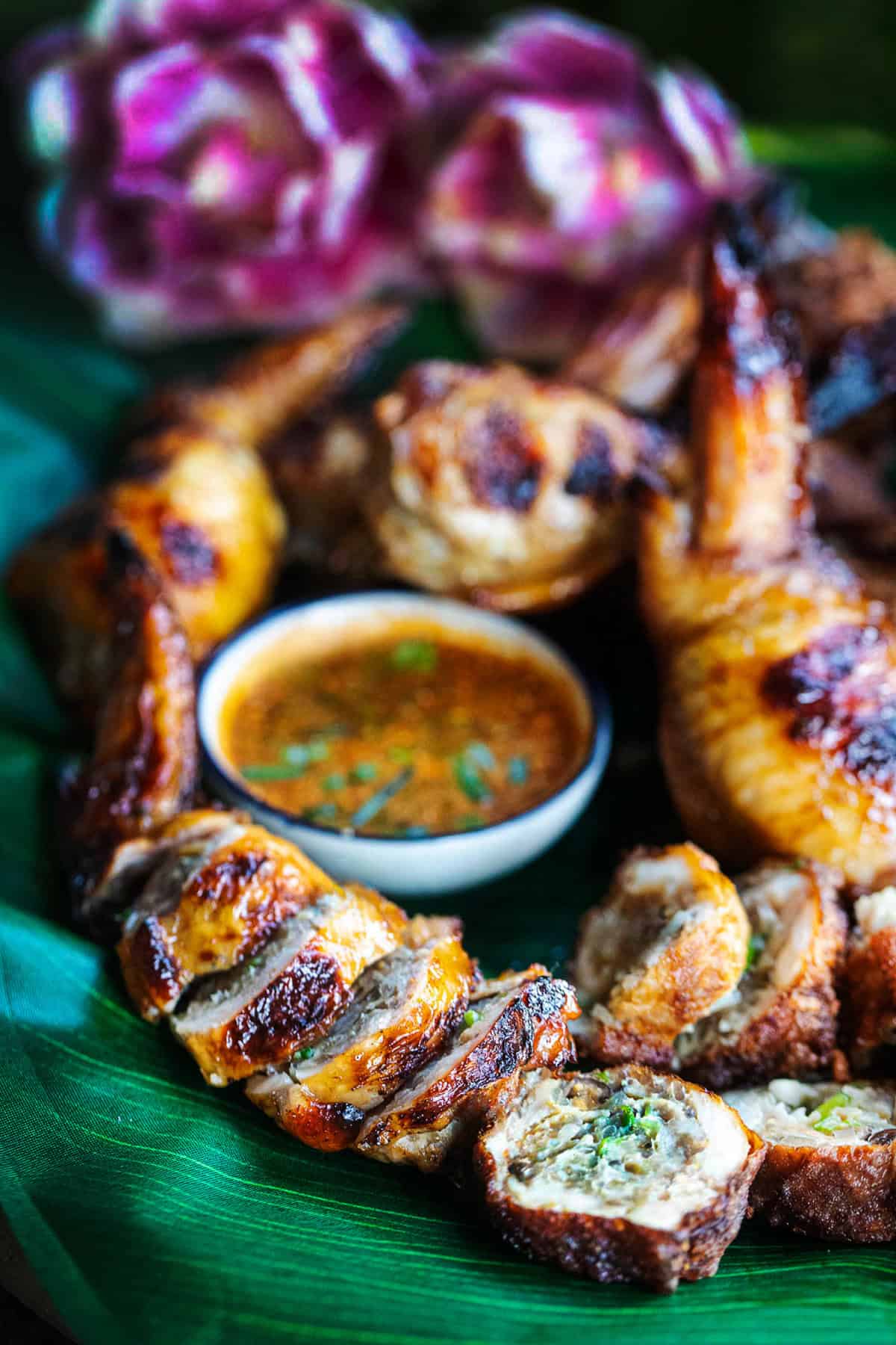Sliced stuffed wings on a platter with dipping sauce.