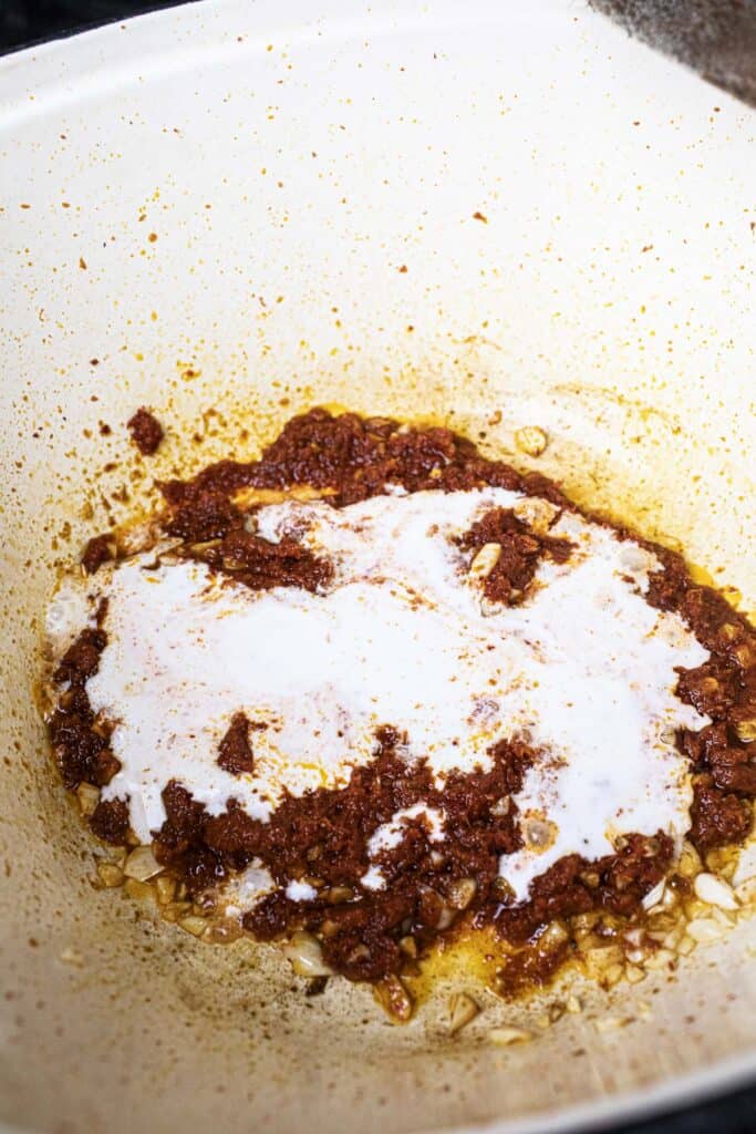 Red curry paste and coconut milk in a pot.
