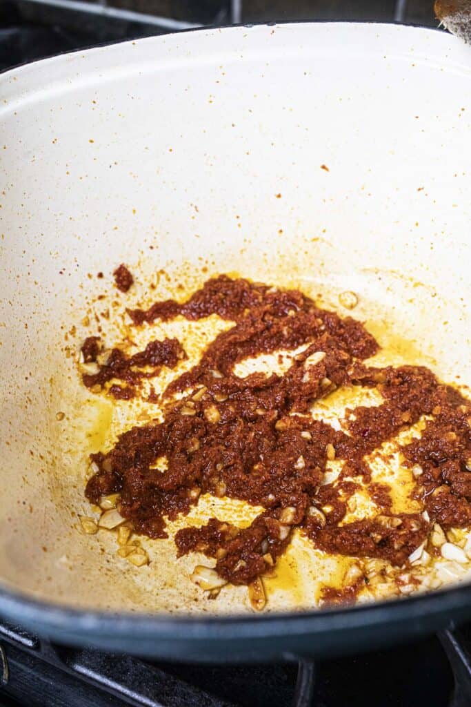 Red thai curry paste in a pot on the stove. 