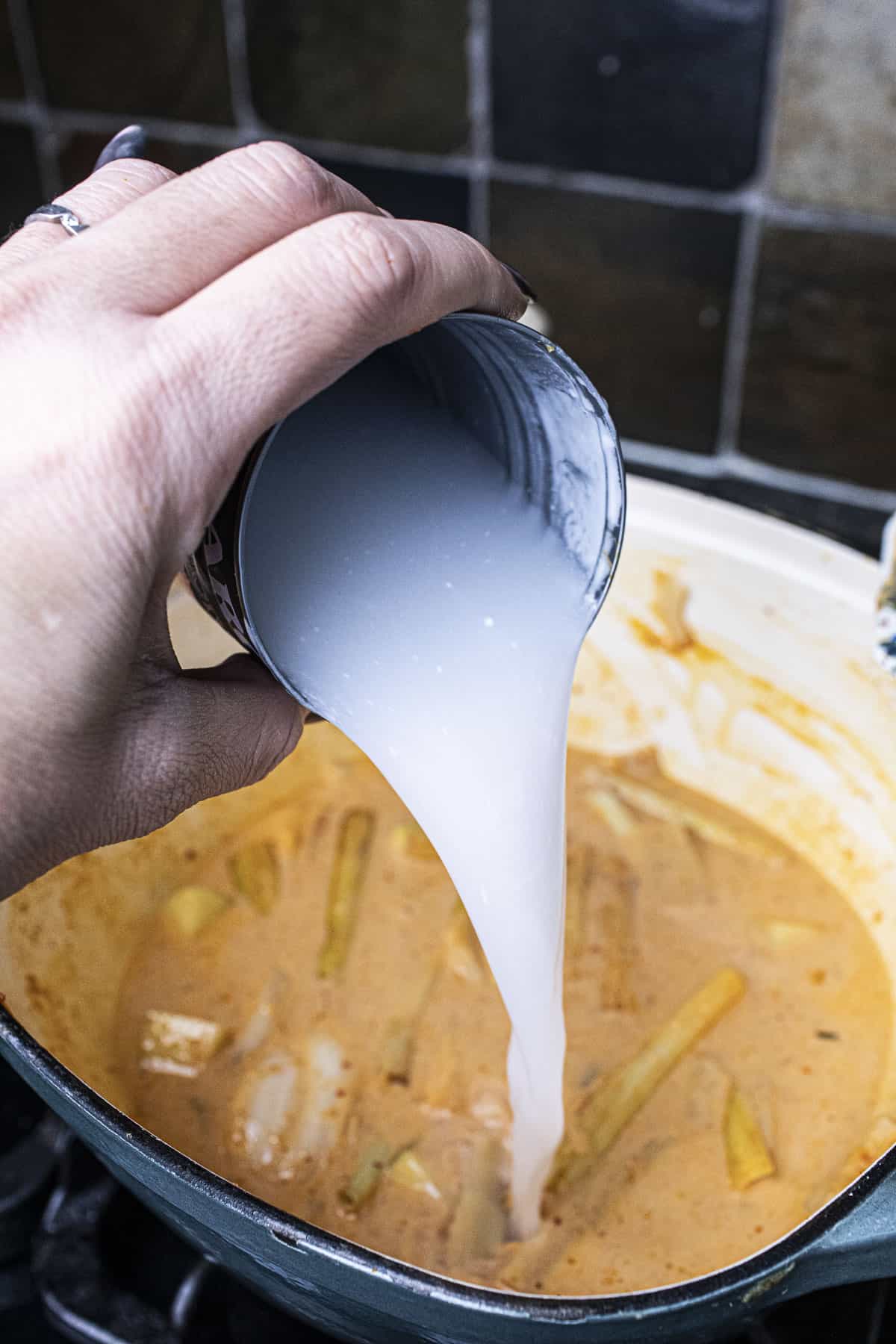 Coconut milk from a can poured in a pot.