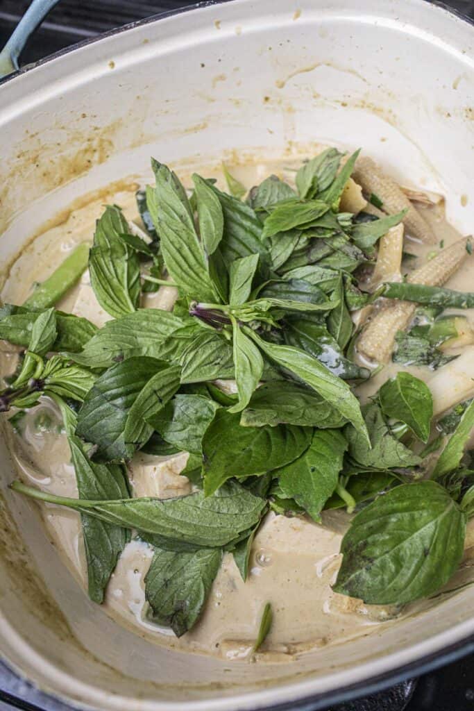 Fresh basil in a pot of green vegetarian curry.