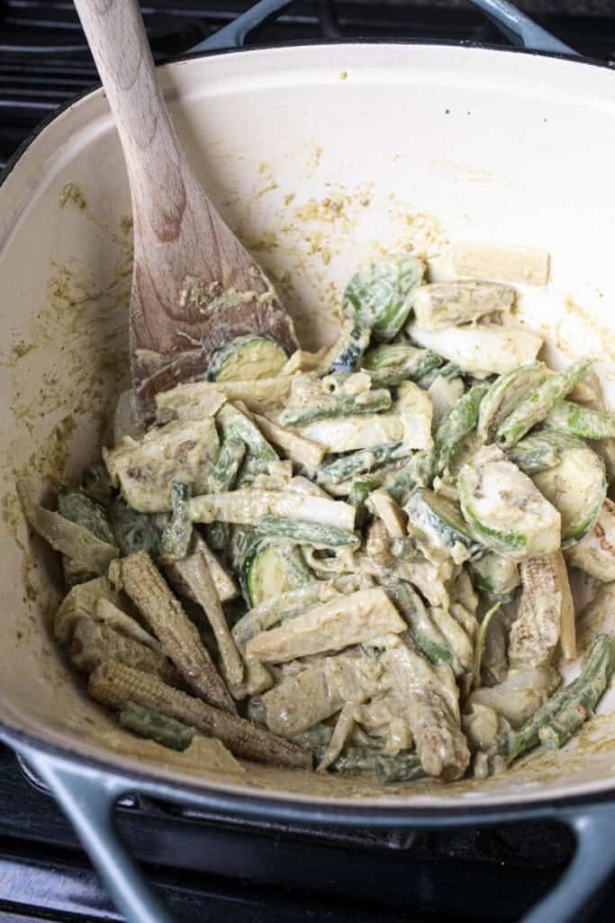 Mixed vegetables in green curry paste in a pot.