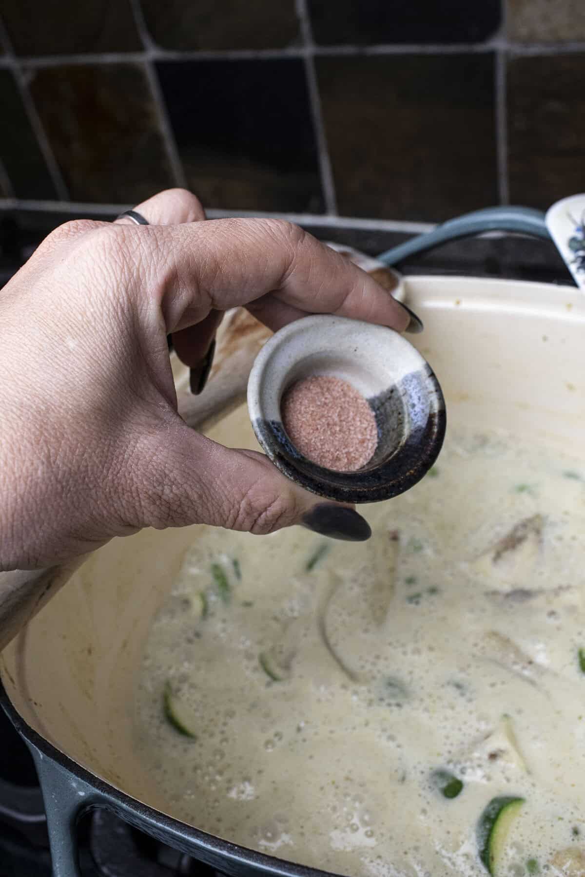 Salt pouring into a pot of vegetarian curry. 