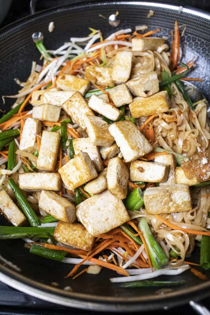Vegetables and tofu with Pad Thai noodles in a wok.