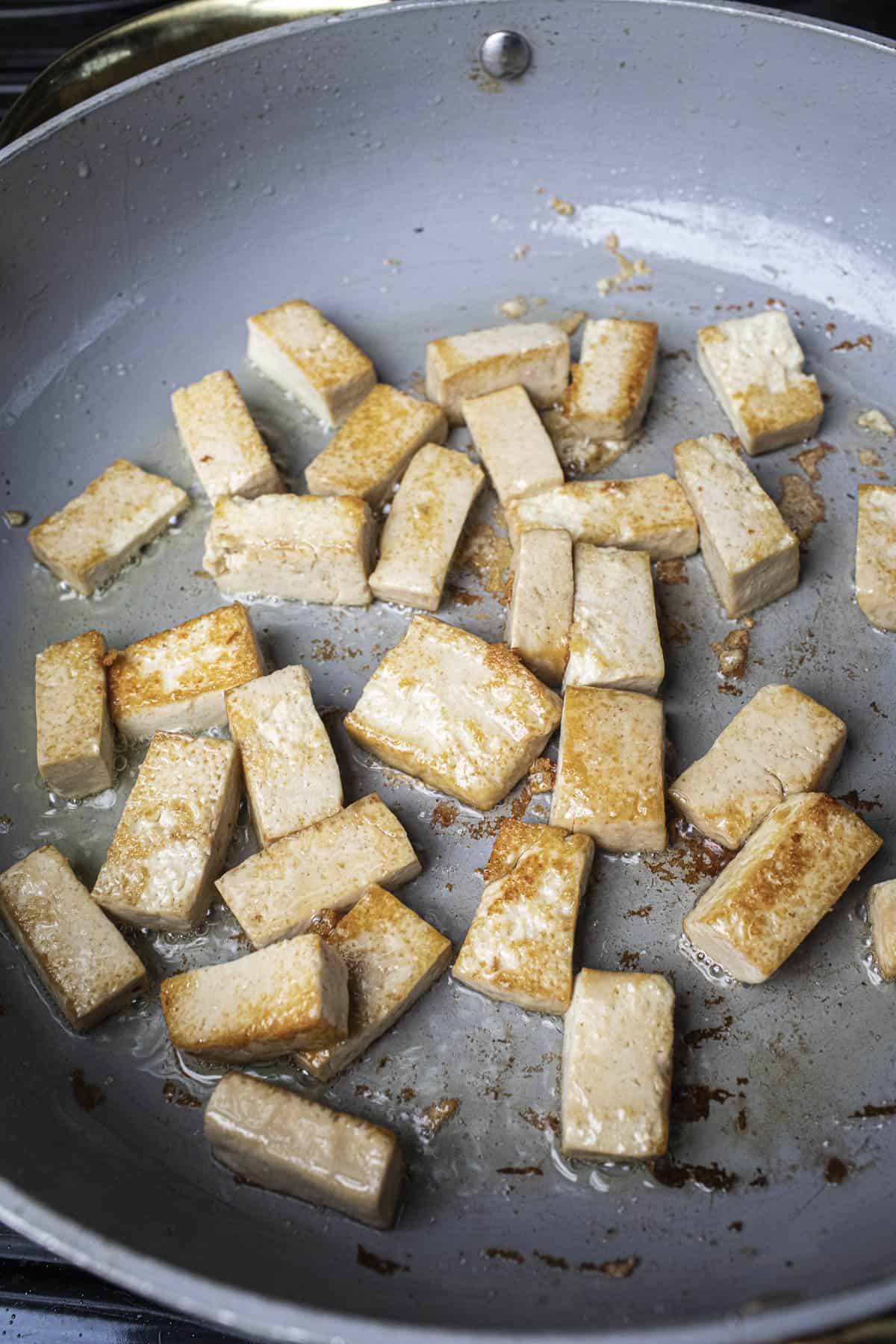 Fried tofu cubes in a pan. 