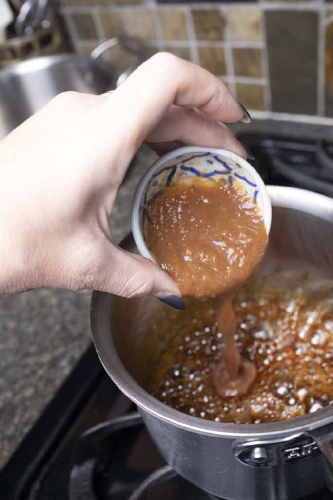 tamarind is poured into a pan with Pad Thai sauce.