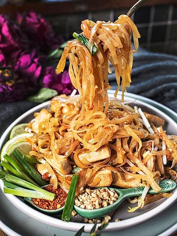 fork lifting Vegetarian Pad Thai from a plate on the table.