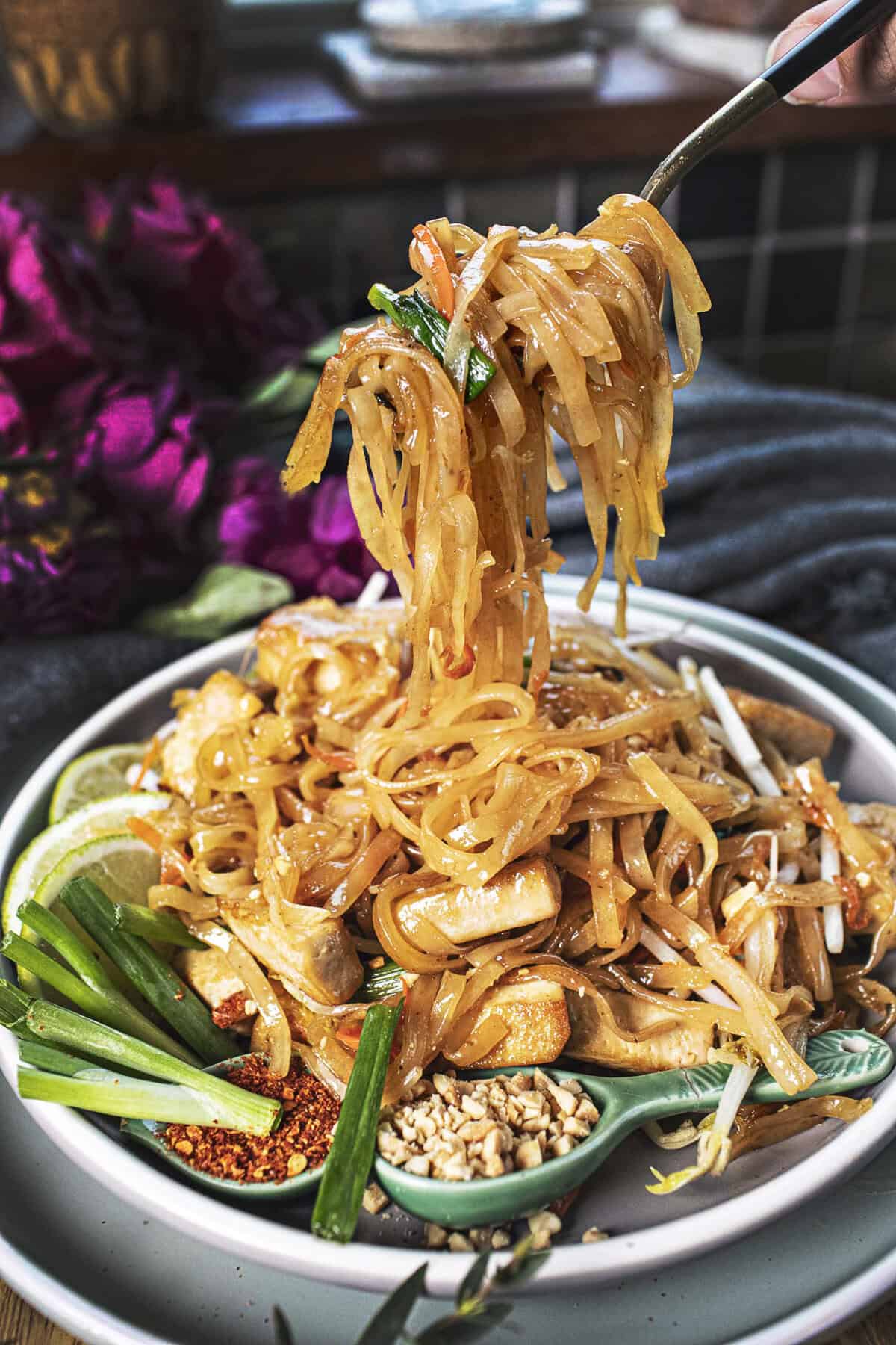 Fork lifting vegetarian pad thai from a plate.