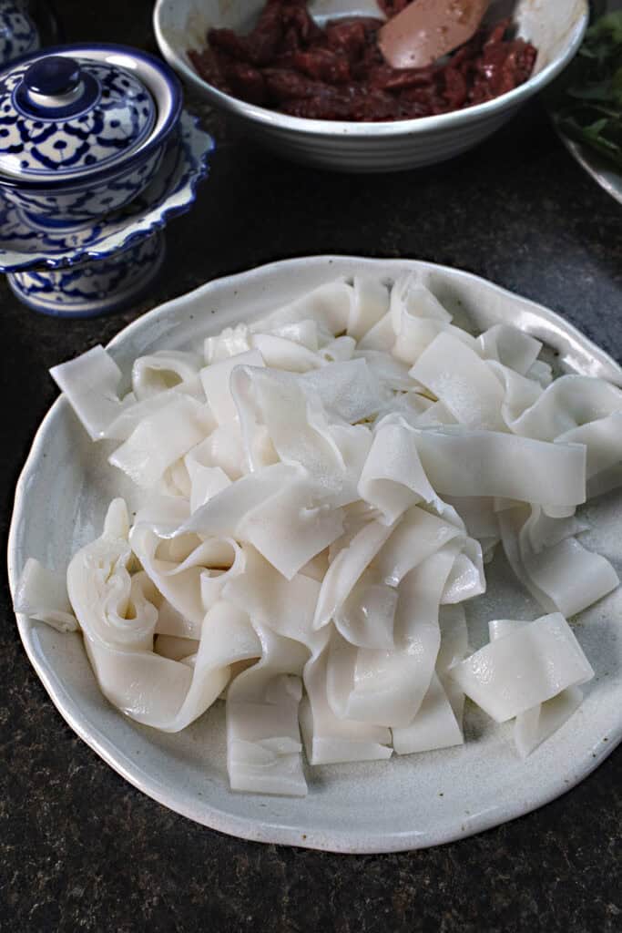 Wide strands of pad see ew noodles on a plate.