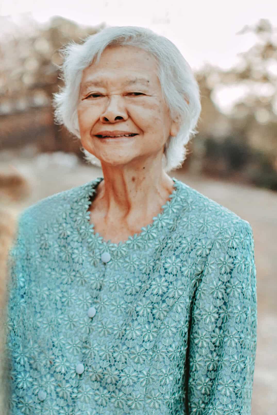 A Thai woman in teal shirt smiling at the camera. 