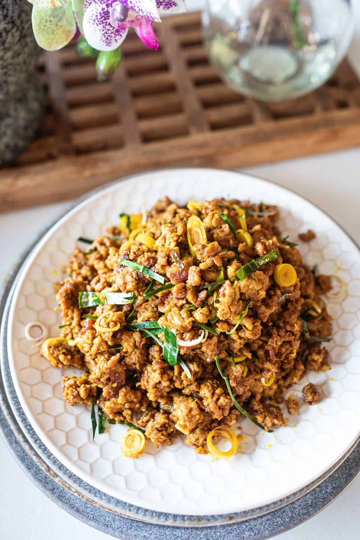 Khua kling moo, ground pork dry curry with herbs sprinkled on top, on plates stacked on top of each other. 
