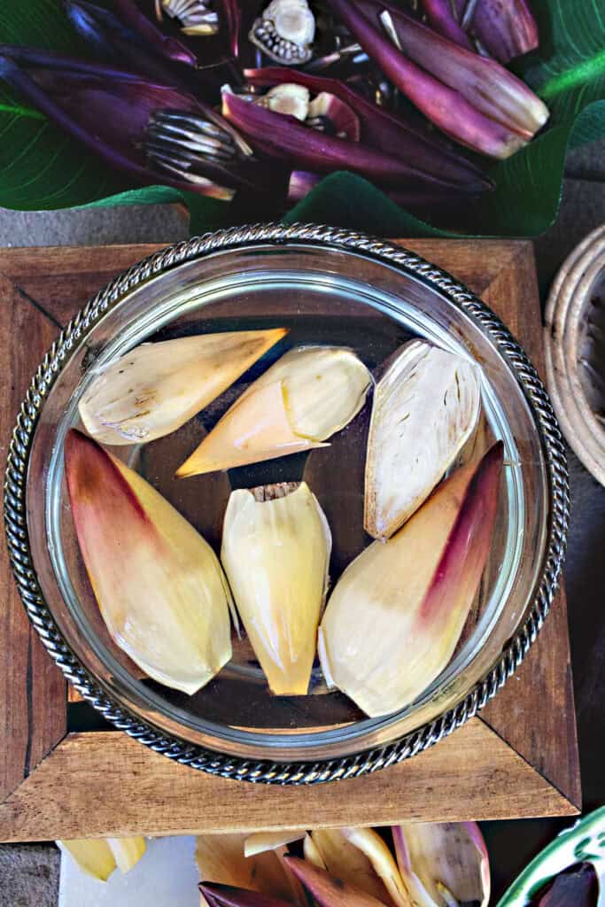 Banana blossom petals soaking in a bowl of water to reduce bitterness—an essential prep step when making Thai banana blossom salad.