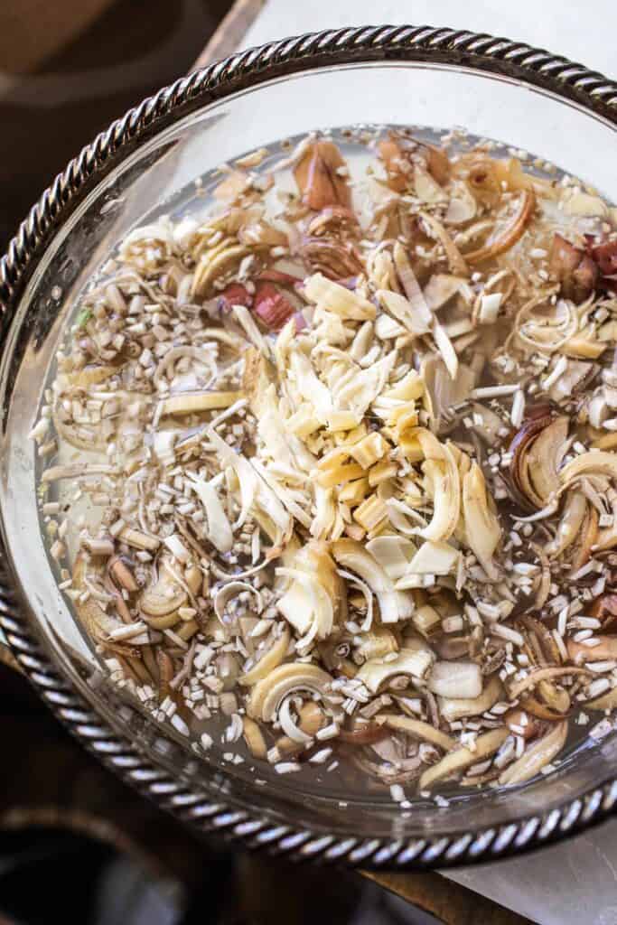 Thinly sliced banana blossoms soaking in water to reduce bitterness and prevent browning—an essential prep step for Thai banana blossom salad.