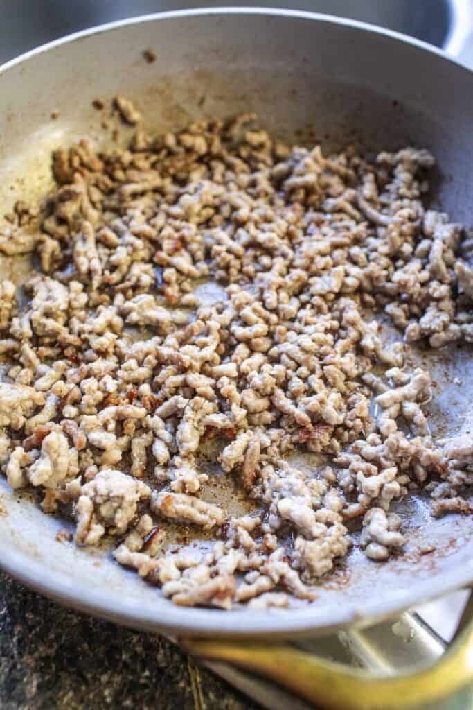 Ground pork cooking in a skillet, lightly browned and ready to be added to Thai banana blossom salad for a savory protein boost.
