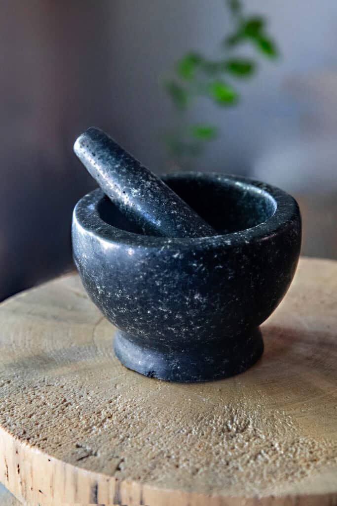 black Stone mortar and pestle on a cutting board.