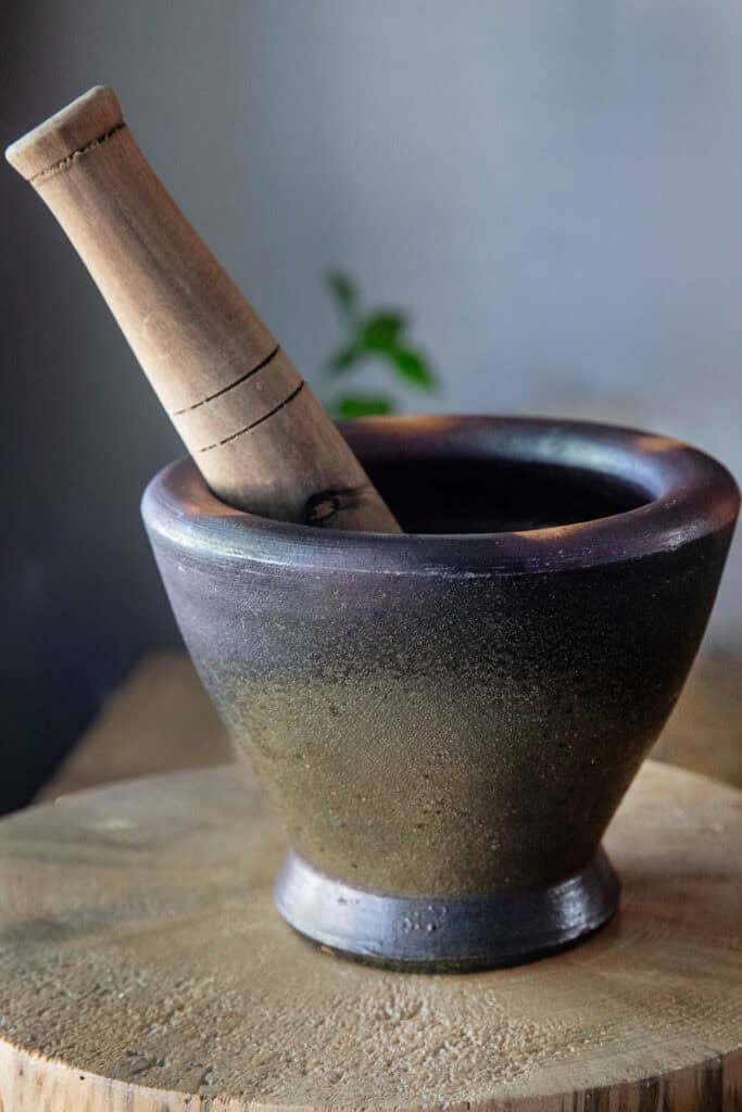 Clay mortar and pestle set on a cutting board.