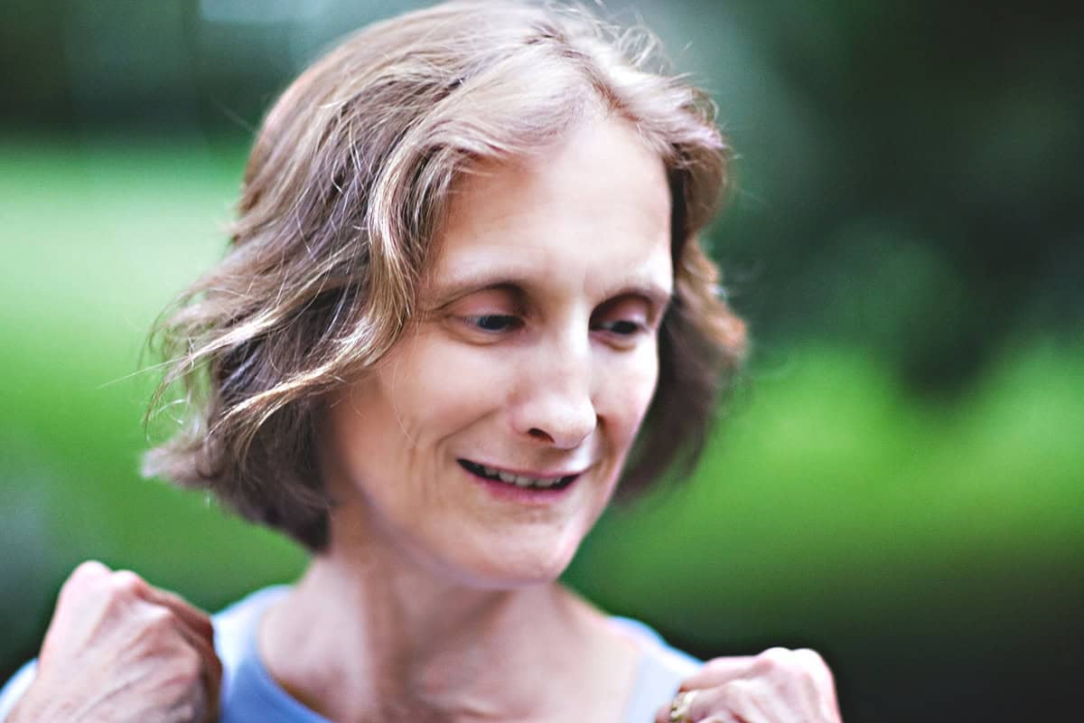 A woman touching her shoulders and smiling. 