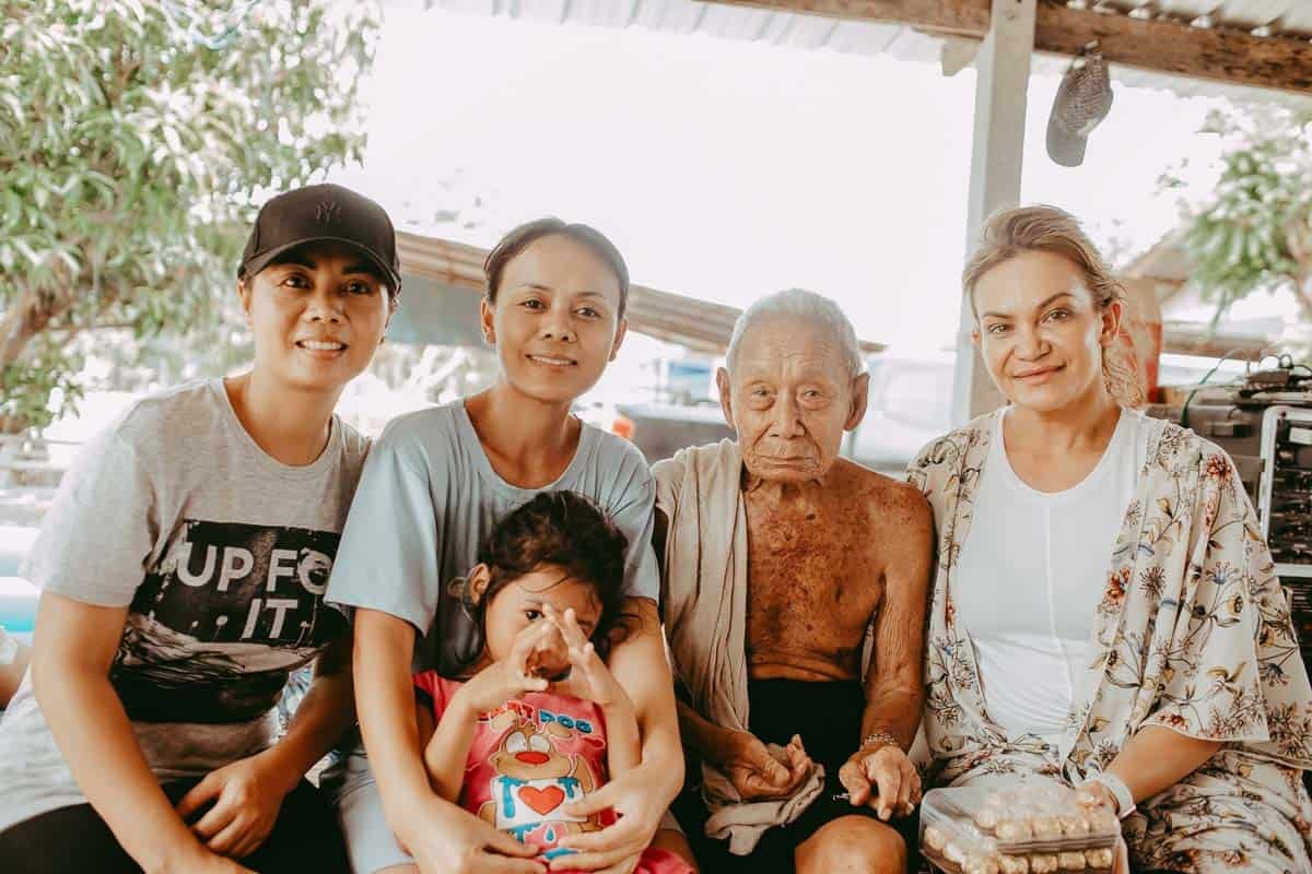 3 women, one old man, and one young child sittin together and looking and smiling at the camera. 