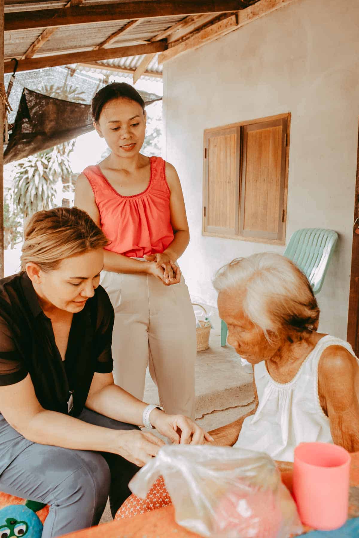 A woman holding an elderly woman's hand while sitting near each other. 