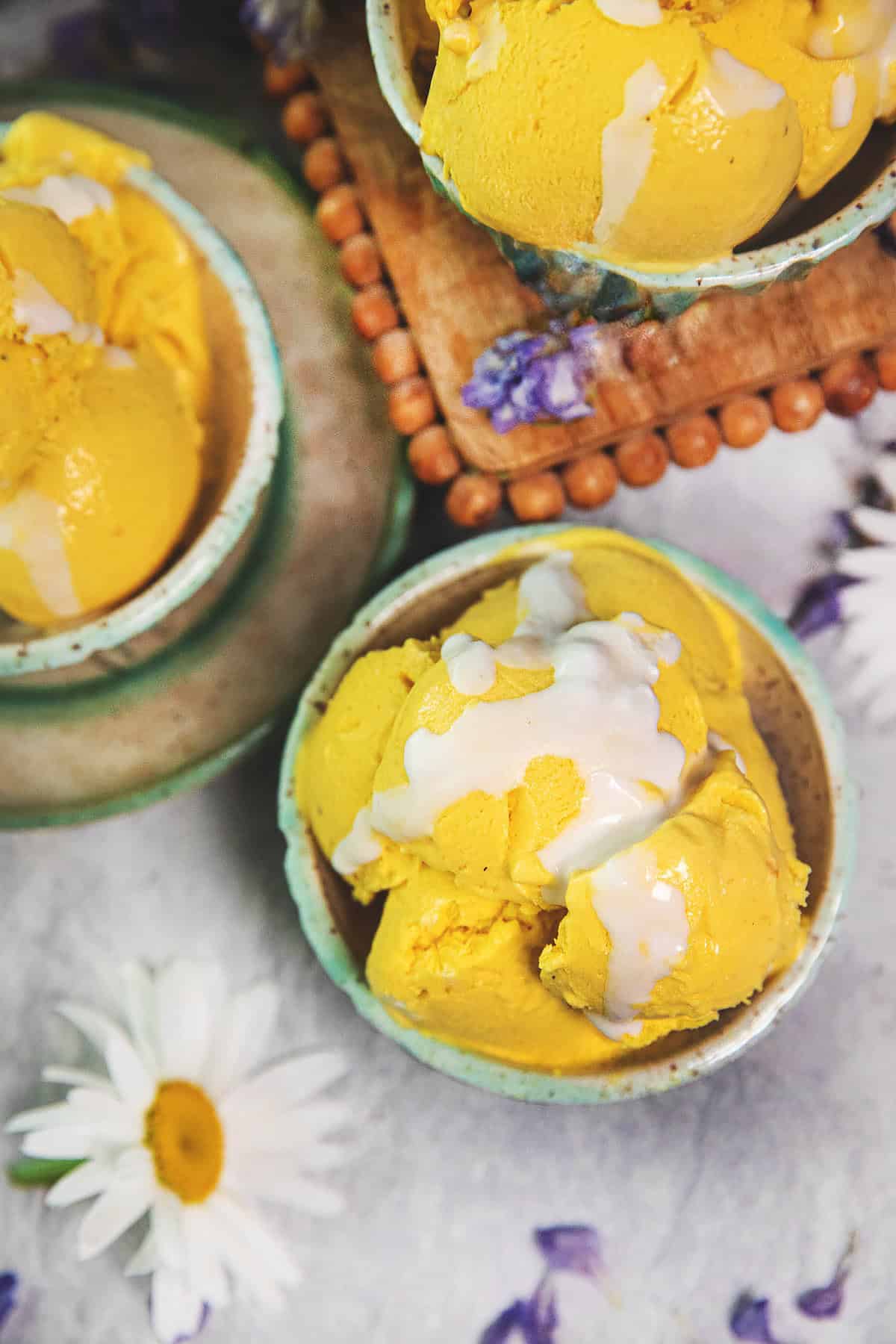 3 small bowls of Thai mango ice cream scoops on a table. 