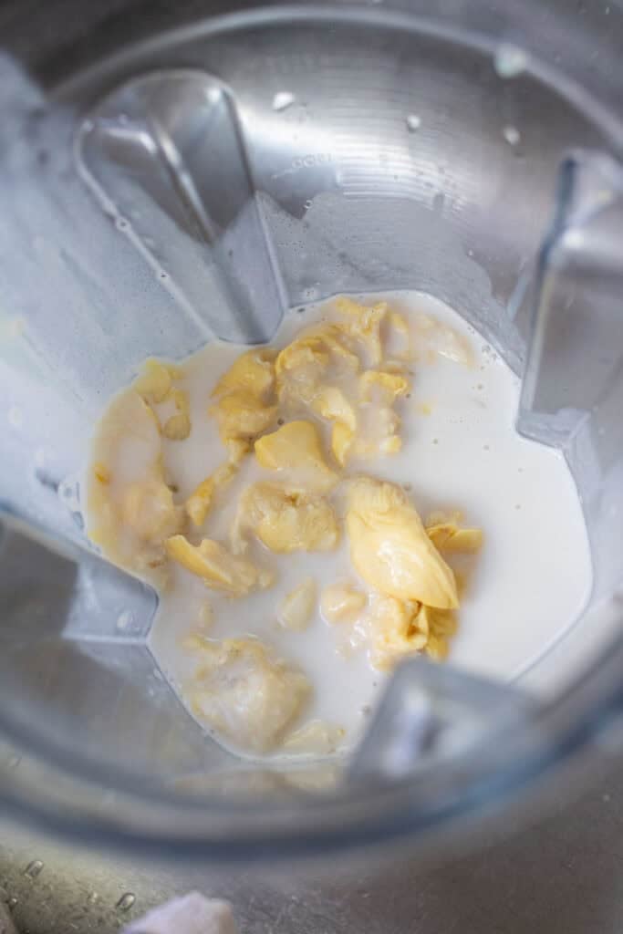 Coconut milk with durian flesh chunks in a food processor. 