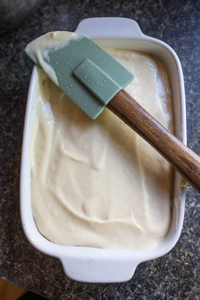 Frozen Durian ice cream in a shallow pan with a spatula on top on a table.