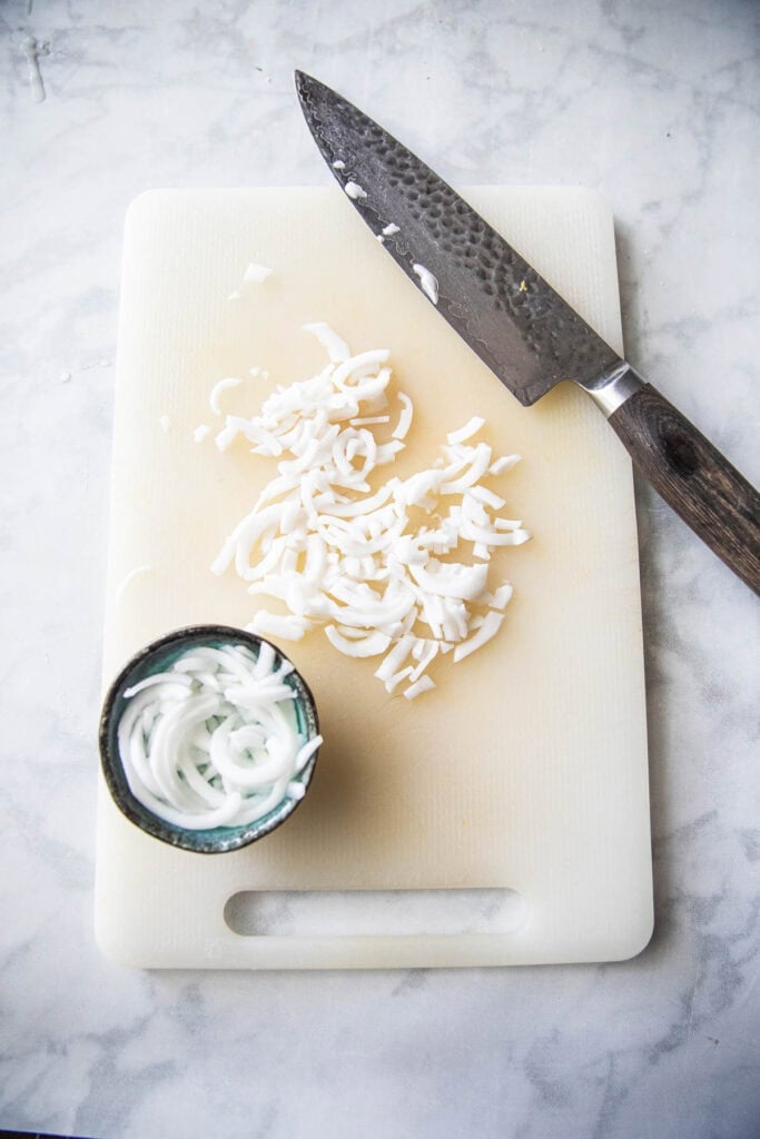 Chopped young coconut meat on a cutting board. 
