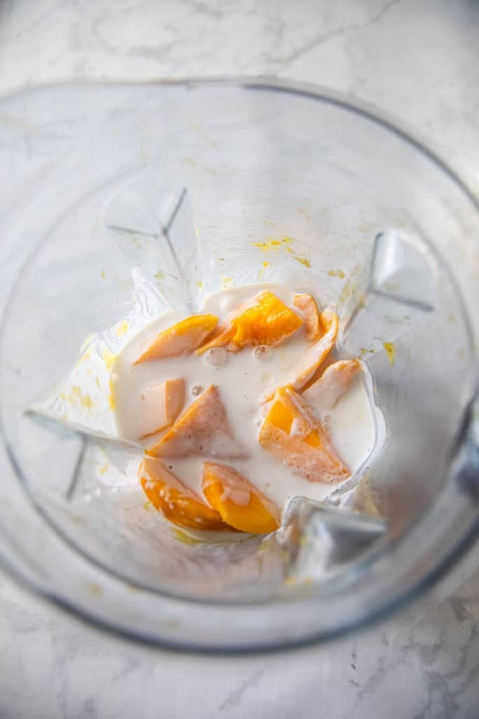 Mango chunks with coconut milk in a food processor.