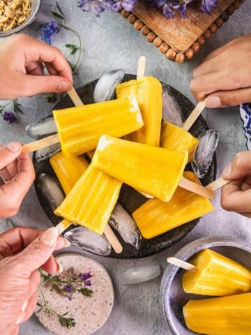 little hands grabbing mango popsicles from a plate.