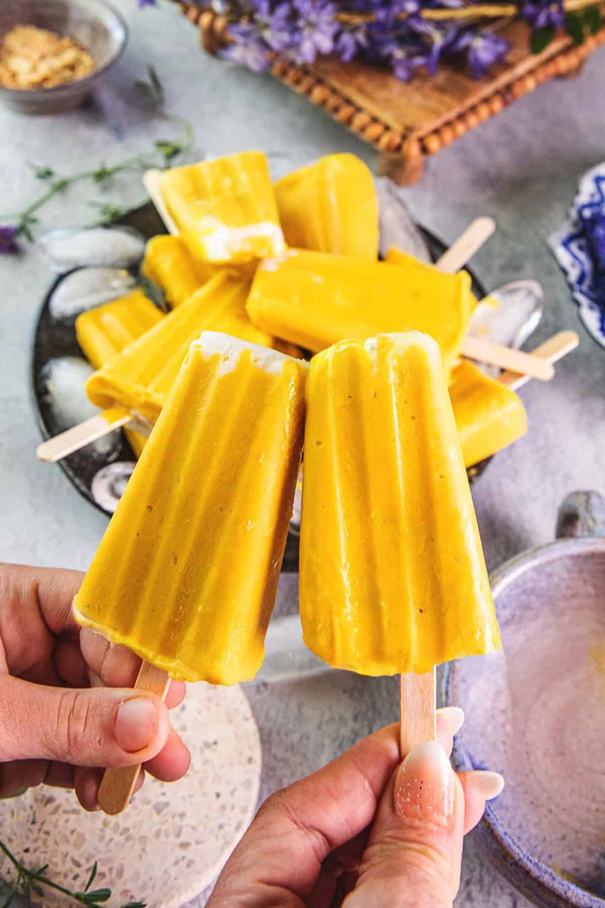 Yellow mango Popsicles with sticks next to each other, with more popsicles in the background. 