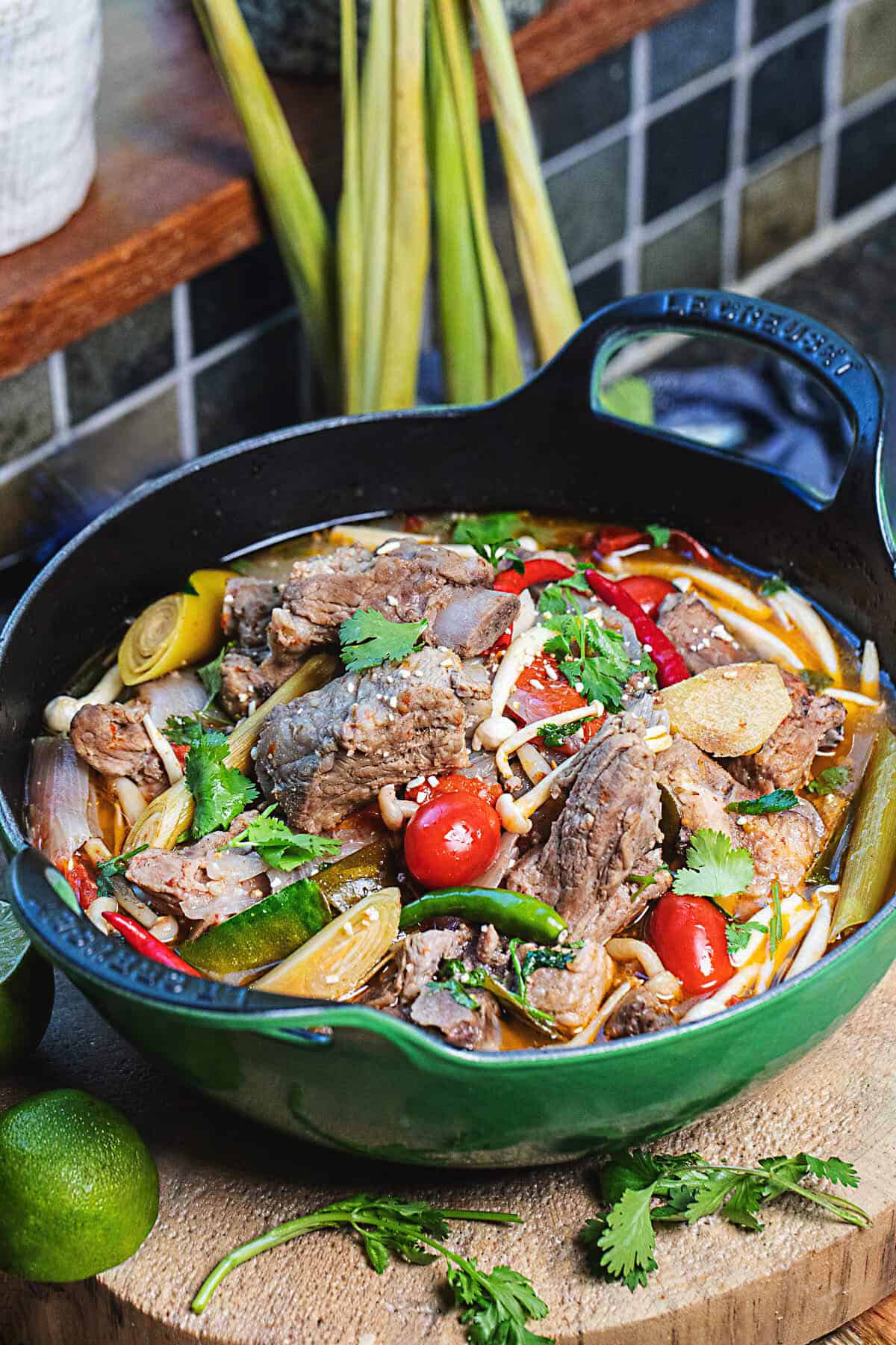 Tom Saap Isaan Soup in a green pot on a cutting board.