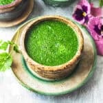 Thai cilantro dressing in a small brown bowl on top on a platter on the table.