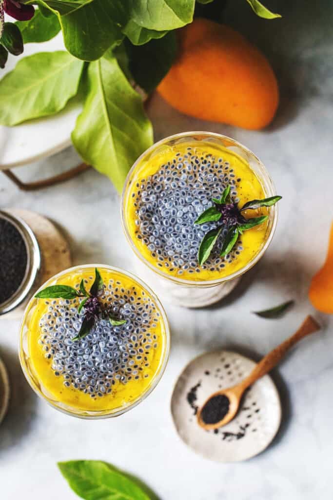 Overhead shots of two glasses of mango smoothie with basil seeds on top as garnish. 