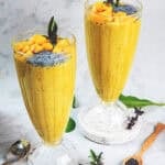 Two glasses of Mango Smoothie on a table with white background.