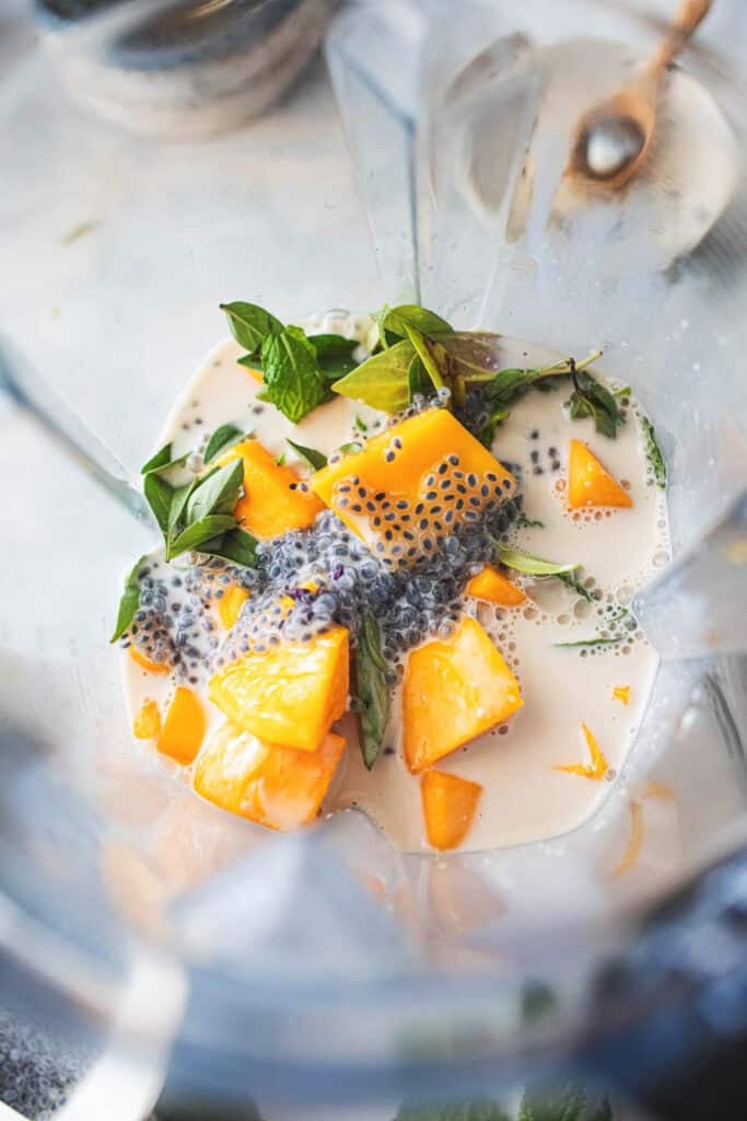 Mango chunks, basil and milk in a food processor for mango smoothie.