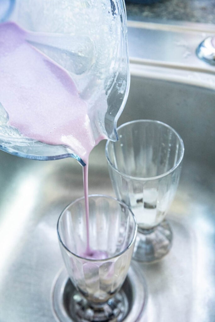Fresh taro bubble tea puree is poured into glasses of boba at the bottom.