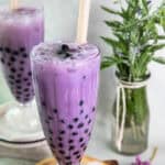 taro boba tea in a glass with black pearls on a table.
