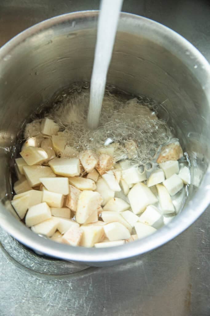 Water rinses taro chunks in a pot. 