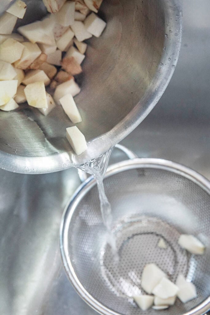 A pot of taro is draining water into a strainer.