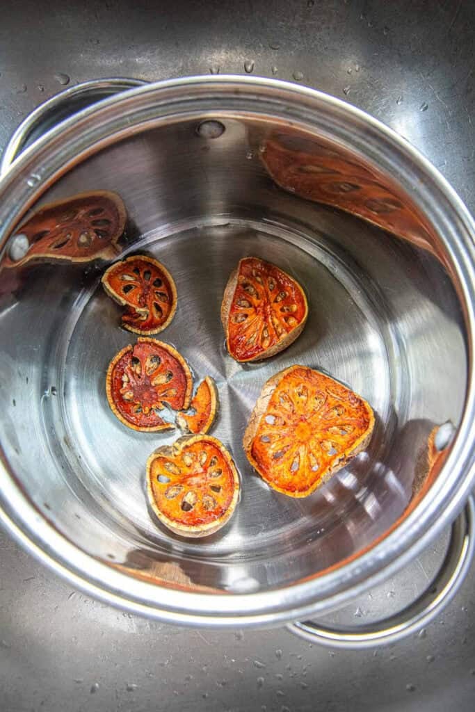 Dried Bael fruit slices in water in a pot.