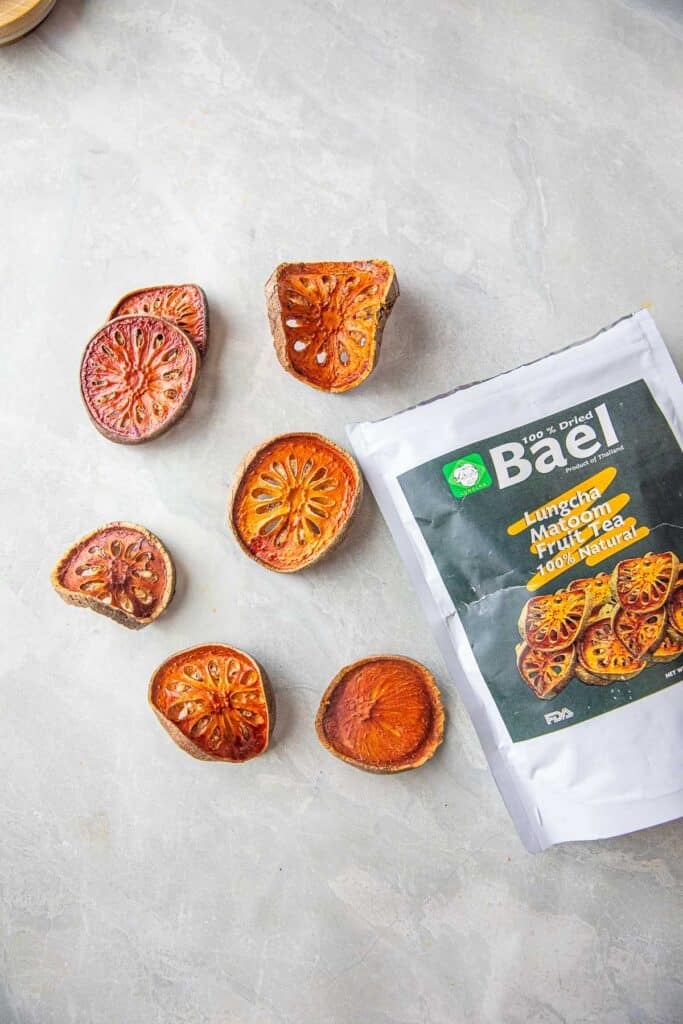Dried Bael fruit slices next to a bag. 