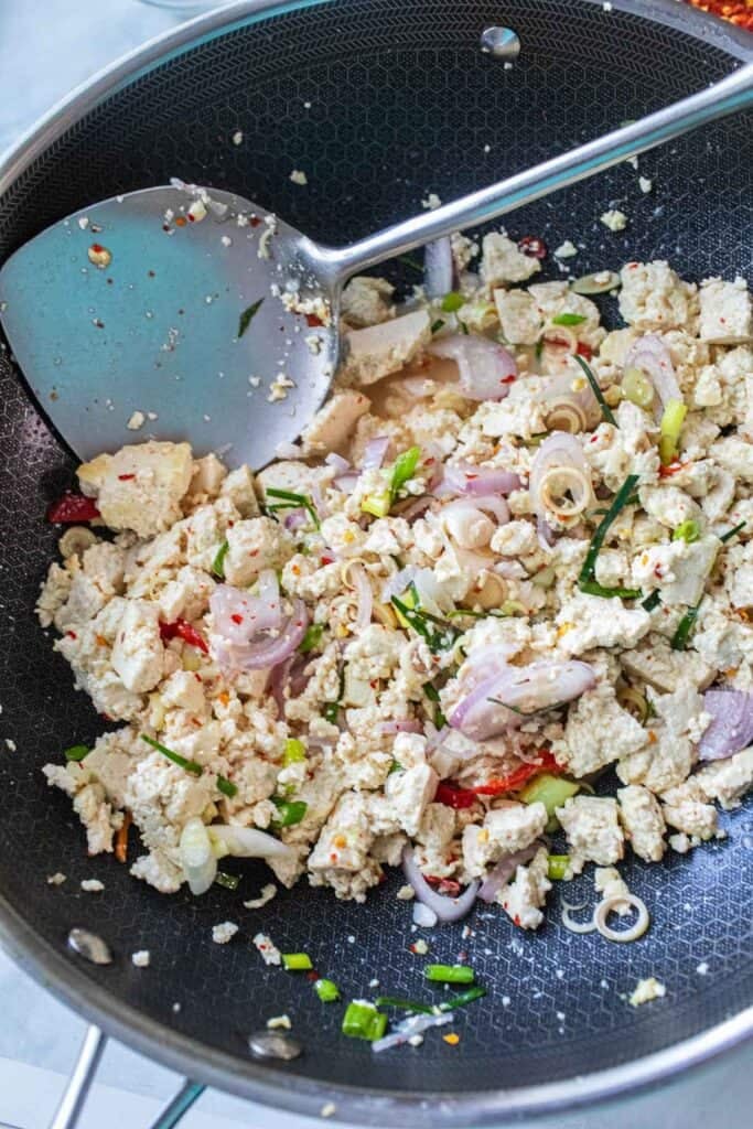 A pile of tofu larb in a wok with a spatula. 