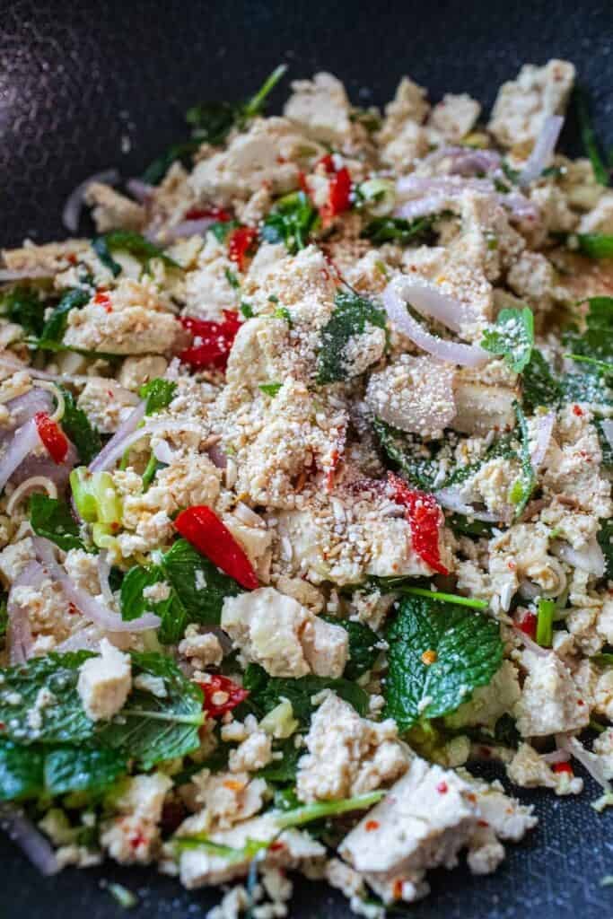 A pile of tofu larb salad with toasted rice powder on top. 